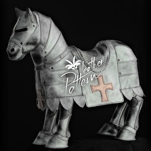 Op de afbeelding: Een handgemaakte, grijze leren paardensculptuur, gekleed in middeleeuws harnas. Het harnas heeft geklonken platen, een zadel en een kruisembleem. De sculptuur staat tegen een zwarte achtergrond, wat de details benadrukt.