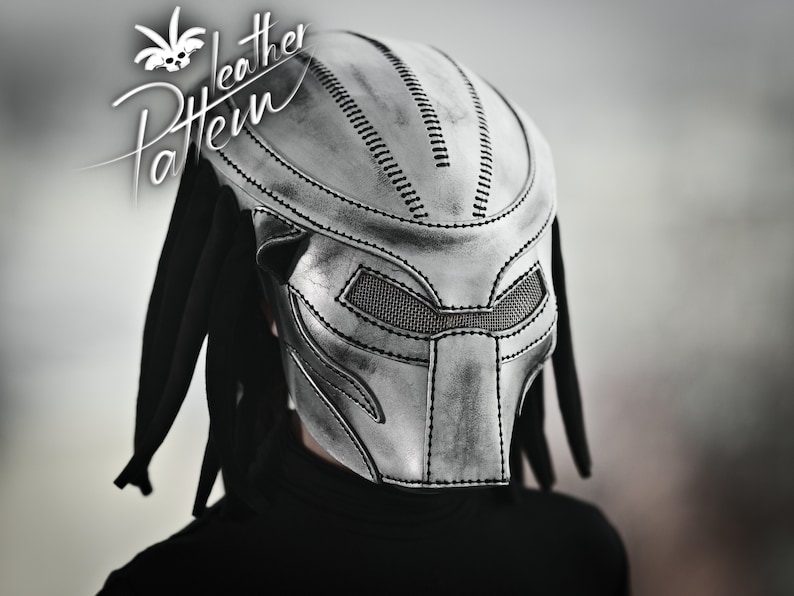 K&ouml;nnte beinhalten: Eine silberne Predator-Maske aus Leder mit schwarzen Dreadlocks. Die Maske hat ein detailliertes Design mit gen&auml;hten Linien und einem Netz-Augenabdeckung.