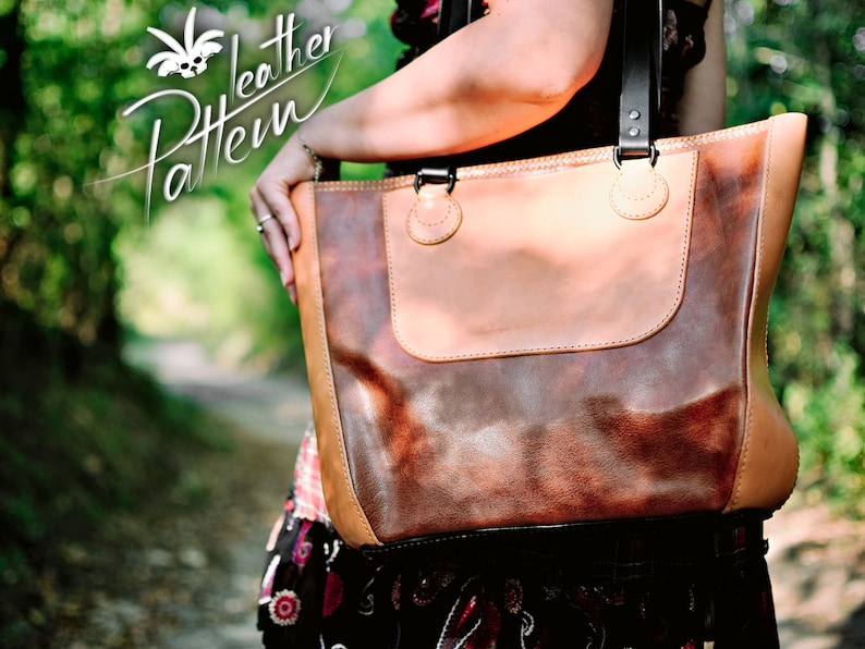 Puede incluir: Un bolso tote de cuero bicolor con un panel central de color marr&oacute;n oscuro jaspeado y paneles laterales y borde superior en cuero color canela claro. El bolso incluye correas negras de cuero con herrajes met&aacute;licos y el texto Leather Pattern.