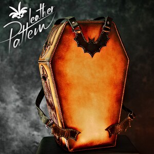 May include: A brown leather coffin-shaped backpack with a bat design on the front. The backpack has adjustable straps and a zip closure.