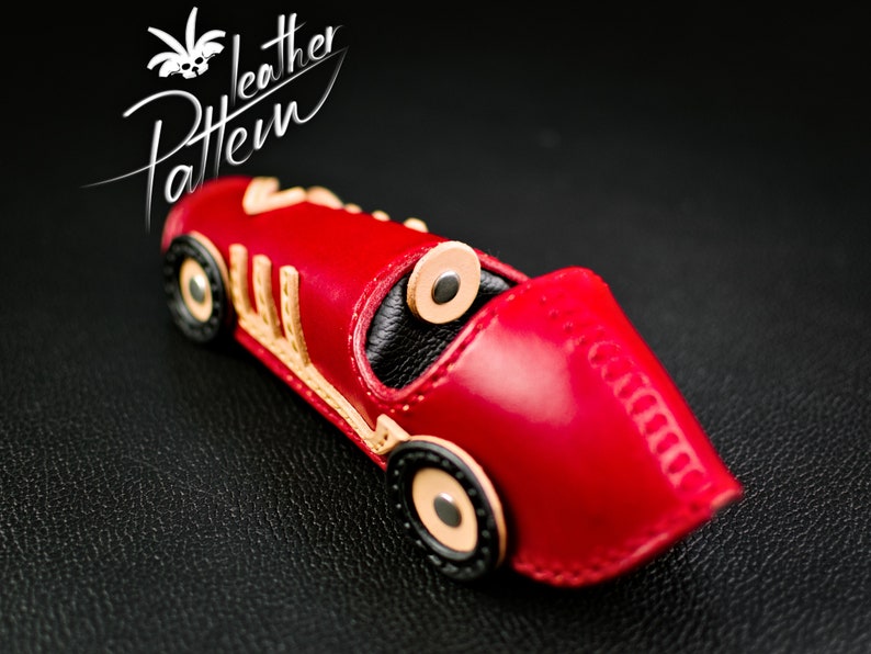 K&ouml;nnte beinhalten: Ein handgefertigtes rotes Leder-Rennauto mit beigen und schwarzen Akzenten. Das Auto hat ein detailliertes Design, einschlie&szlig;lich R&auml;dern und Cockpit. Das Bild enth&auml;lt auch den Text "leather Pattern".