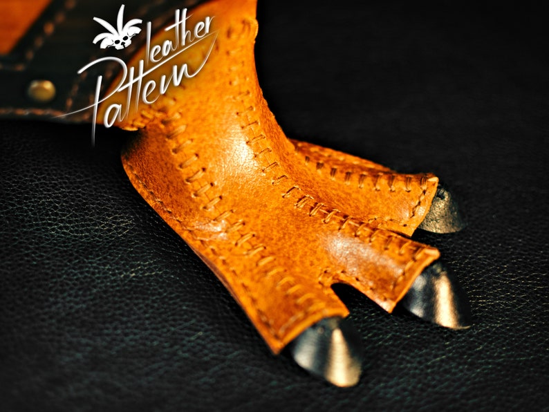 K&ouml;nnte beinhalten: Nahaufnahme einer braunen Lederkralle mit N&auml;hten und schwarzen Metallverzierungen. Die Kralle liegt auf einem schwarzen Hintergrund. "Leather Pattern" ist in orangefarbener Schrift oben links geschrieben.