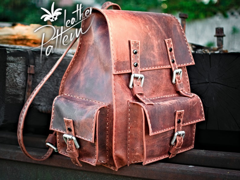 May include: A brown leather backpack with two large front pockets and two adjustable buckles. The backpack has a distressed look and is made of high-quality leather.