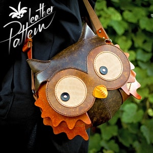 May include: A brown leather owl-shaped crossbody bag with large, round eyes, a yellow beak, and orange feathers. The bag is worn by a person wearing a black shirt.