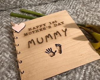 May include: A wooden book with a pink heart and the text "Happy 1st Mother's Day Mummy" with hand and footprint outlines.