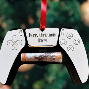 May include: White and black PlayStation controller Christmas ornament with a red ribbon and a personalized tag that says "Merry Christmas Harry".