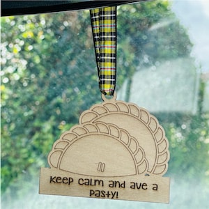 Può includere: Ciondolo per auto in legno con un nastro a quadri giallo e nero. Il ciondolo ha la forma di un pasticcio e ha il testo "keep calm and ave a pasty!"