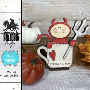 Puede incluir: Un proyecto de artesanía de madera con un personaje de diablo rojo sosteniendo un tenedor y de pie en una taza blanca con un corazón rojo y el texto "Steaming Hot".