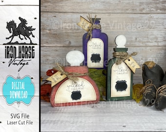 May include: Three wooden potion bottles with labels that say "The Wicked Cauldron" and have a cauldron graphic. The bottles are painted in shades of red, purple, and green. The bottles are sitting on a wooden surface with fall leaves.