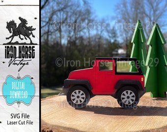 Puede incluir: Un jeep de juguete rojo con detalles negros y ruedas, sentado en un tocón de árbol de madera frente a dos árboles verdes. El jeep es un archivo de corte láser para descarga digital.