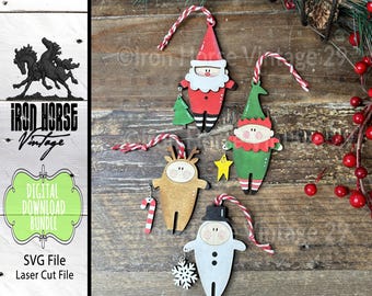 May include: Four wooden Christmas ornaments featuring a Santa Claus, elf, reindeer, and snowman. Each ornament is painted with bright colors and has a whimsical design. The ornaments are hanging from twine.