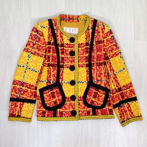 May include: A yellow and red plaid blazer with black trim and a small label that reads "C'EST UNIQUE".