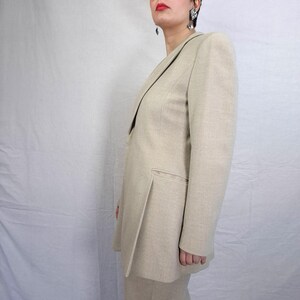Puede incluir: Blazer beige y pantal&oacute;n a juego. El blazer tiene solapa con muescas y un bolsillo. El traje est&aacute; hecho de una tela texturizada. El conjunto es de color neutro, adecuado para diversas ocasiones.