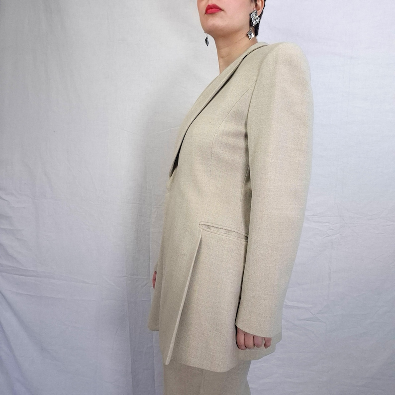 Puede incluir: Blazer beige y pantal&oacute;n a juego. El blazer tiene solapa con muescas y un bolsillo. El traje est&aacute; hecho de una tela texturizada. El conjunto es de color neutro, adecuado para diversas ocasiones.