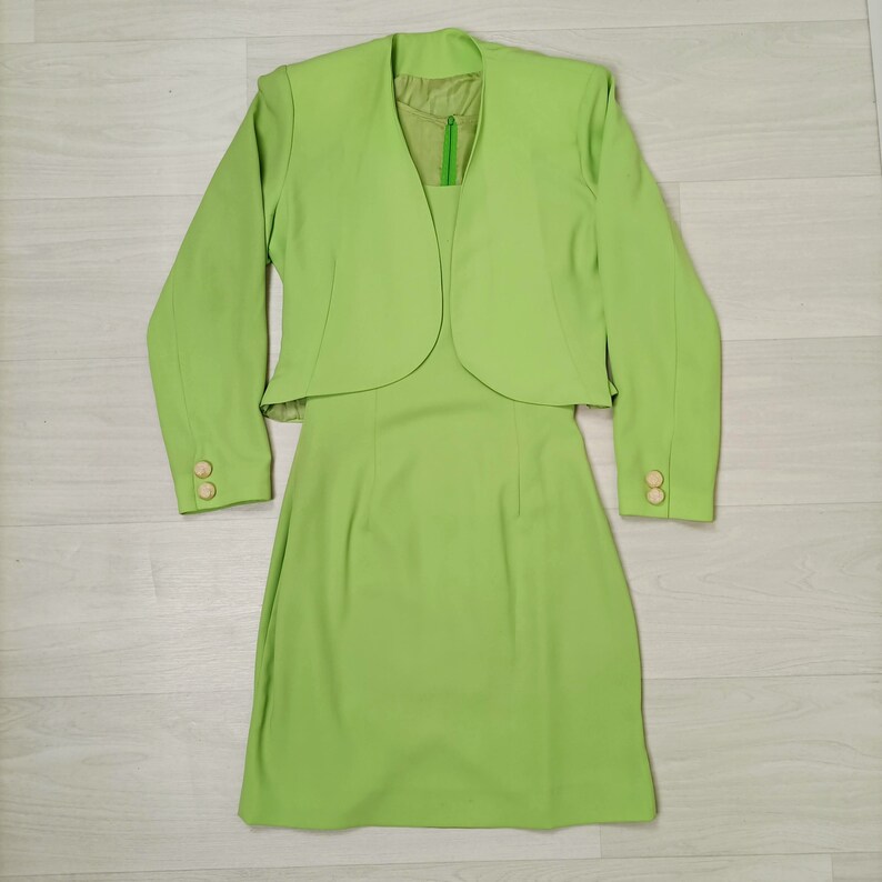 May include: A lime green dress suit with a short jacket and a knee-length skirt.
