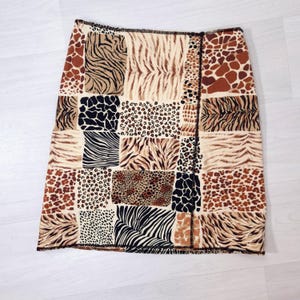 Può includere: Una gonna al ginocchio con un design patchwork che incorpora vari motivi animalier. La gonna presenta strisce di zebra, leopardo e tigre nelle tonalità del marrone, nero e beige. La gonna è realizzata in un tessuto morbido.
