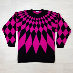 May include: A black and cerise pink geometric pattern sweater. The sweater features a repeating diamond pattern that radiates from the neckline. The sleeves are long and the neckline is crew. The sweater is made of a soft material.