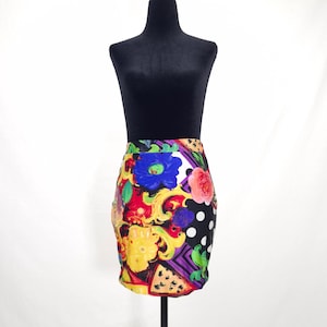 May include: A high-waisted mini skirt featuring a vibrant, multi-colored print with large blue and pink flowers, yellow scrollwork, purple geometric patterns, and black sections adorned with white polka dots, finished with a straight hemline.