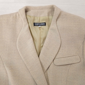 Puede incluir: Blazer beige con solapa de muesca y un solo bolsillo. El forro interior es de color beige claro. La etiqueta dentro de la blazer dice "GIORGIO ARMANI A. MILANO BORGO NUOVO 11".