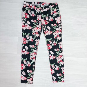 May include: Black skinny jeans with a floral print featuring pink and red flowers on a black background.