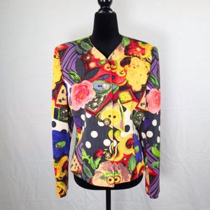 May include: A colorful, vintage blazer with a vibrant floral and abstract pattern. The jacket features a V-neck, long sleeves, and gold-toned buttons. The design includes red, yellow, blue, and purple hues, with polka dots and floral motifs.
