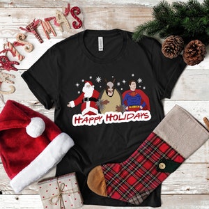 May include: Black t-shirt with a graphic of Santa Claus, a donkey, and Superman with the text "Happy Holidays".