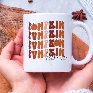May include: White ceramic mug with a brown, orange, and beige design that says "Pumpkin Spice" with a small pumpkin graphic.