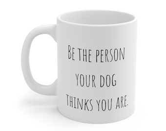 May include: White ceramic coffee mug with black text that reads "Be the person your dog thinks you are."