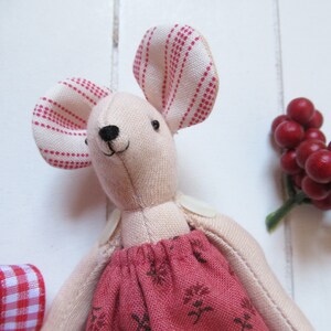 May include: A pink fabric mouse doll with red and white striped ears and a red floral dress.