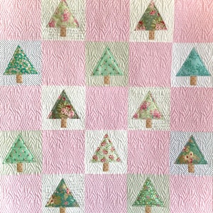 Può includere: Una trapunta rosa e bianca con un motivo a scacchi con 16 alberi di Natale triangolari con stampa floreale verde e bianca.