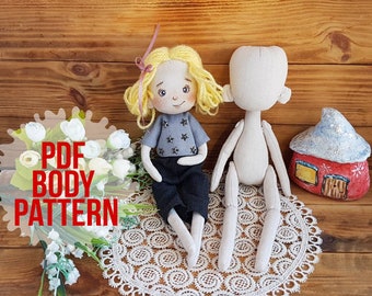 May include: A PDF pattern for a doll body. The pattern is shown next to a finished doll with blonde hair, a grey shirt with stars, and black trousers. The doll is sitting on a white lace doily.