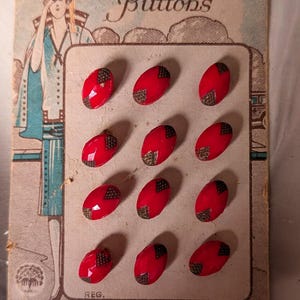 May include: A vintage card of red oval buttons with a decorative gold and black corner design. The card is labelled "Fashionable Buttons" with an illustration of a woman in a flapper dress. The card is from Czecho-Slovakia.