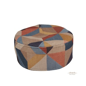 May include: A round, patterned hat with a geometric design. The hat features a mix of colors, including orange, blue, brown, and yellow. The hat is made of fabric and has a rounded top and a band around the base.