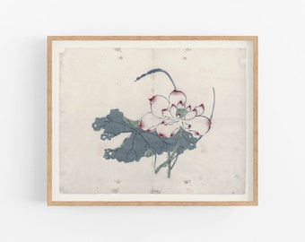 Può includere: Una stampa incorniciata di una delicata illustrazione ad acquerello dipinta a mano di un fiore di loto bianco con accenti rosa e una foglia blu-grigia. L'opera d'arte è su uno sfondo color crema.