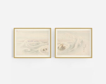 Op de afbeelding: Twee ingelijste prints van Japanse aquarel schilderijen die golven tonen die breken in de oceaan. De prints zijn in gouden lijsten en hebben een licht beige achtergrond.