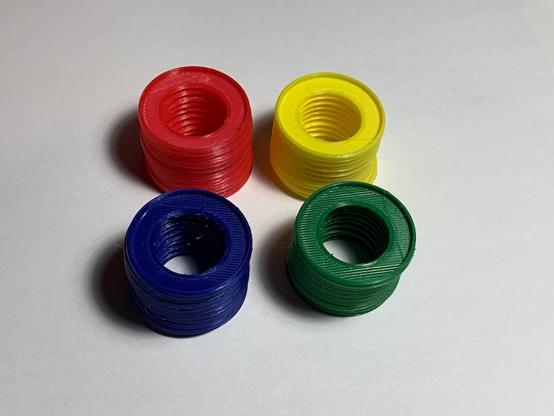 Puede incluir: Cuatro pilas de anillos de pl&aacute;stico de colores. Los anillos son rojos, amarillos, verdes y azules. Cada pila mide aproximadamente 5 cm de alto.