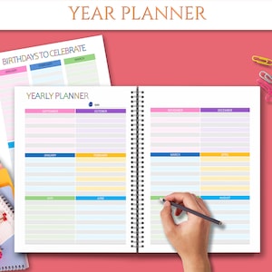May include: A yearly planner with a colorful design. The planner has a spiral binding and is open to the months of September, October, November, and December. The planner also includes a section for birthdays to celebrate.