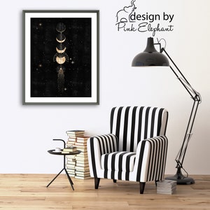 Puede incluir: Una impresi&oacute;n enmarcada con fondo negro y fases lunares doradas. La impresi&oacute;n est&aacute; colgada en una pared blanca sobre un sill&oacute;n de rayas blancas y negras. El texto "design by Pink Elephant" es visible en la esquina superior derecha de la imagen.