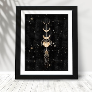 Puede incluir: Una impresi&oacute;n enmarcada en negro y dorado con un dise&ntilde;o celestial. La impresi&oacute;n presenta una cadena de lunas y estrellas doradas sobre un fondo negro.
