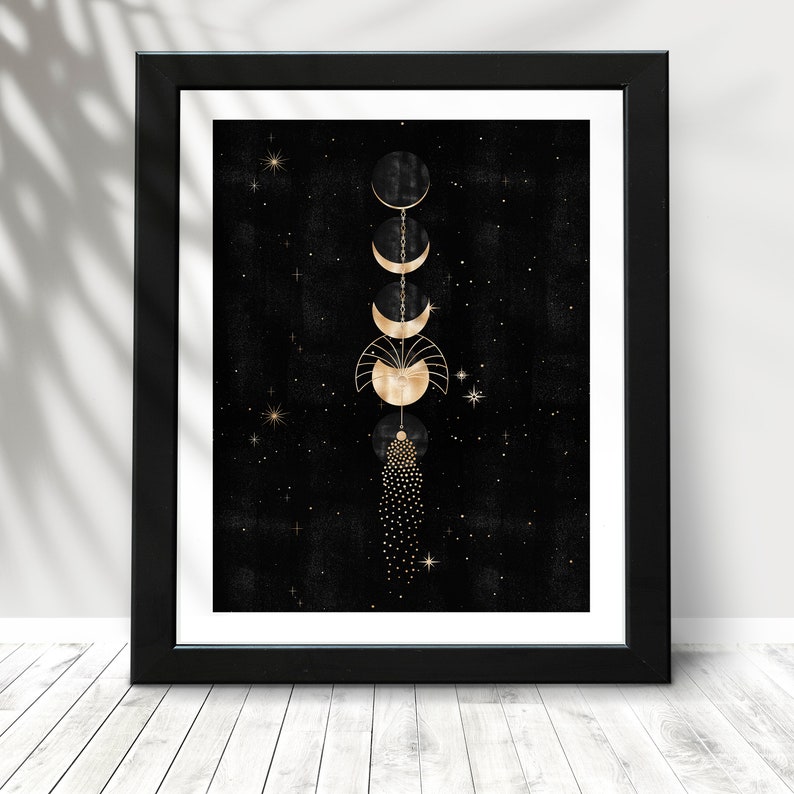 Puede incluir: Una impresi&oacute;n enmarcada en negro y dorado con un dise&ntilde;o celestial. La impresi&oacute;n presenta una cadena de lunas y estrellas doradas sobre un fondo negro.