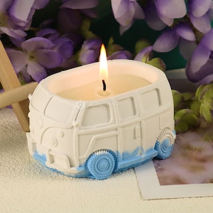 Może przedstawiać: Biała i niebieska świeca w kształcie starego vana z zapaloną świeczką w środku.