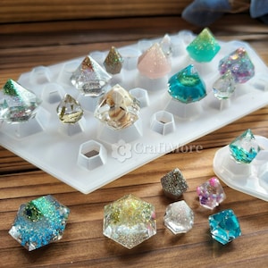 May include: A silicone mold with 12 diamond-shaped cavities, filled with colorful resin gems. The gems are decorated with glitter and other embellishments. The mold is on a wooden surface with several finished resin gems.