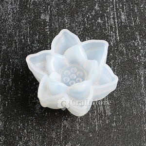 May include: A white silicone mold shaped like a lotus flower with a detailed center. The mold is designed for creating resin crafts.