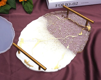 May include: A white and purple resin tray with gold glitter and gold accents. The tray has two gold metal handles and a scalloped edge.