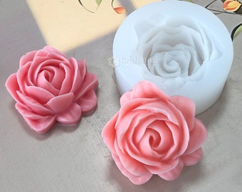May include: A silicone mould for making rose-shaped decorations. The mould is white and has a single rose design. Two pink roses made with the mould are shown.
