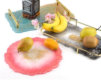 May include: Three resin trays with gold leaf accents and gold metal handles. The trays are in different colors: blue, gray, and pink. The blue tray has a bottle of Jack Daniel's Tennessee Whiskey on it. The gray tray has bananas and pears on it. The pink tray has a pear and an orange on it.
