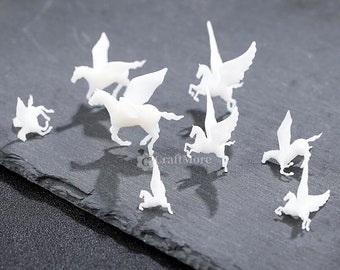 Op de afbeelding: Een set van negen witte plastic miniatuur gevleugelde paarden, of pegasi, in verschillende poses. De paarden kijken allemaal in verschillende richtingen en hebben uitgespreide vleugels. De paarden staan op een donkergrijs oppervlak.