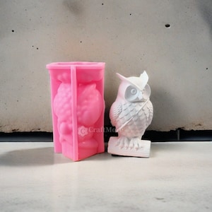 Könnte beinhalten: Rosa Silikonform zum Herstellen einer Eulenfigur. Die Form ist in zwei Hälften geteilt und zeigt das detaillierte Design der Eule. Neben der Form ist eine weiße Eulenfigur zu sehen.