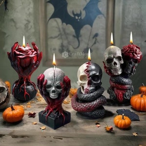 May include: Five Halloween-themed candles, each featuring a skull design. One candle is a red rose with a skull in the center, another is a skull with a snake wrapped around it, and the other three are skulls with hands holding them.