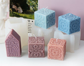 May include: Five decorative candles in different shapes and colors. The candles are in the shape of a house, a square, and a cube. The candles are decorated with floral patterns.